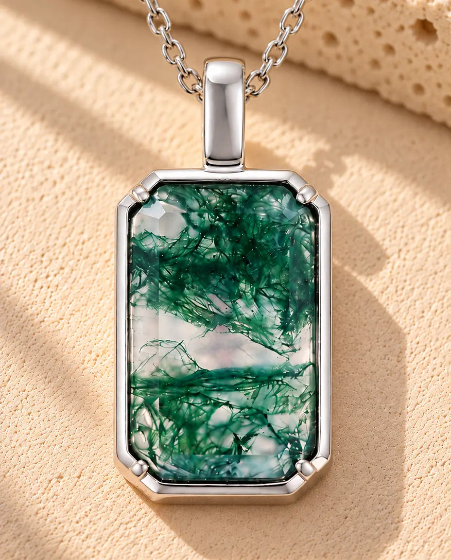 Rectangle Moss Agate Pendant Necklace in 925 Sterling Silver - lying on a cream textured surface beside a travertine block