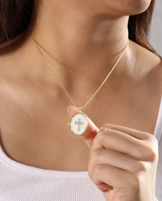 Woman wearing white enamel cross photo locket necklace in gold tone