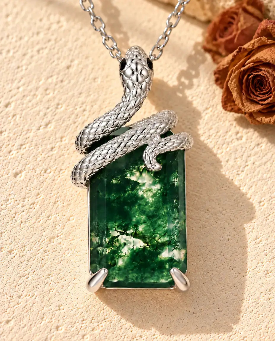 Moss Agate Snake Necklace in 925 Sterling Silver - lying on a cream textured surface beside a travertine block