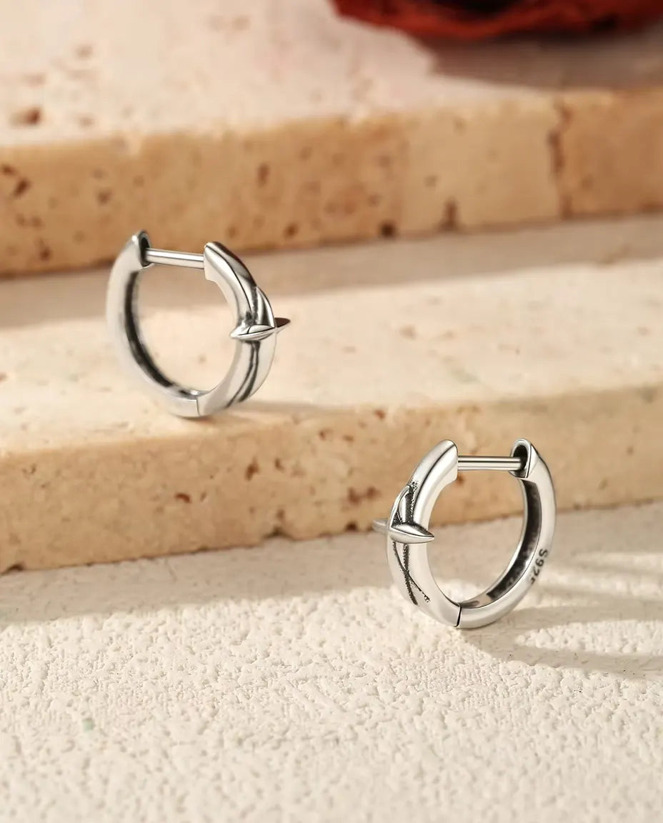 Star Huggie Hoop Earrings in 925 Sterling Silver - the pair resting on travertine steps