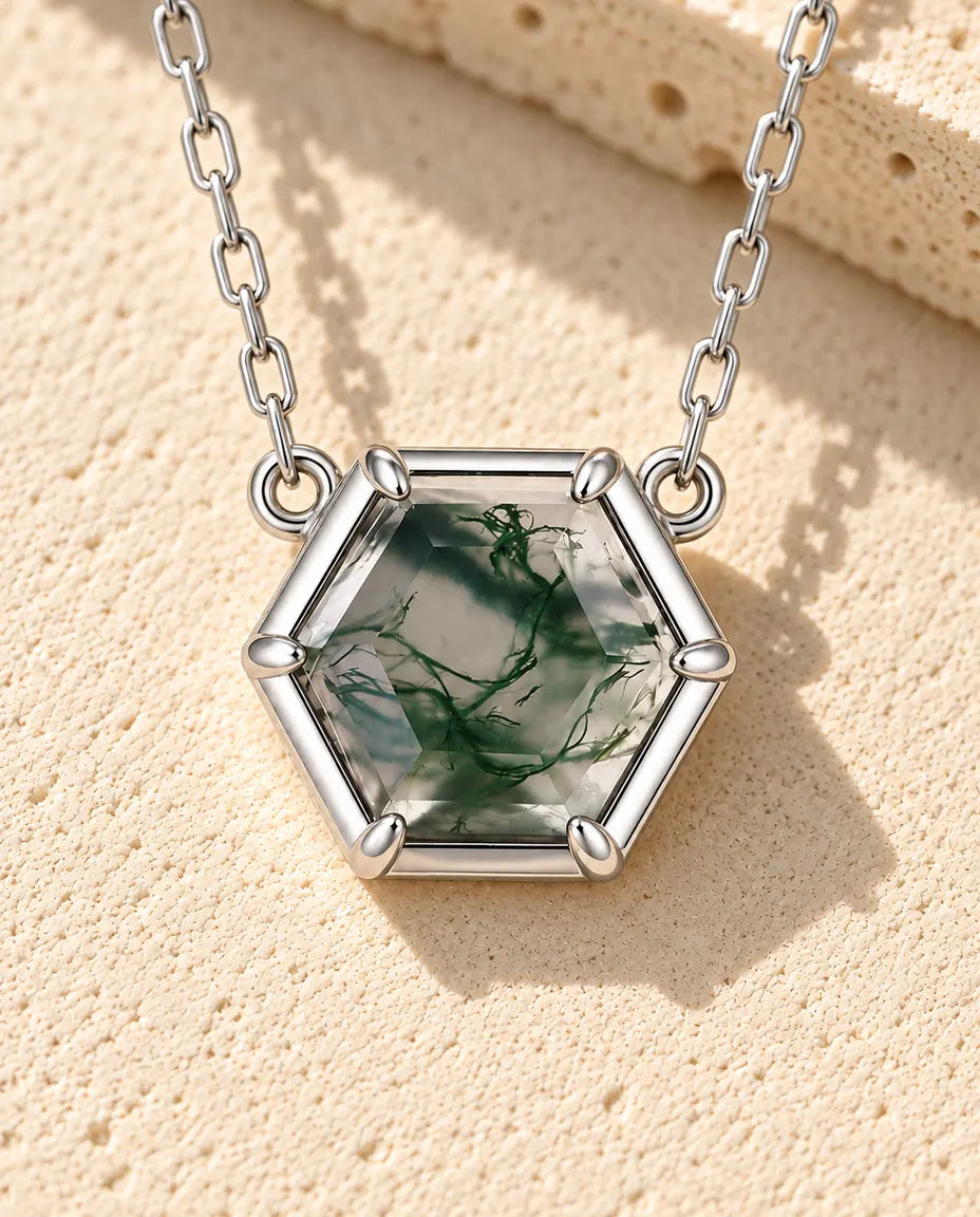 Hexagon Moss Agate Necklace in 925 Sterling Silver - lying on a cream textured surface beside a travertine block