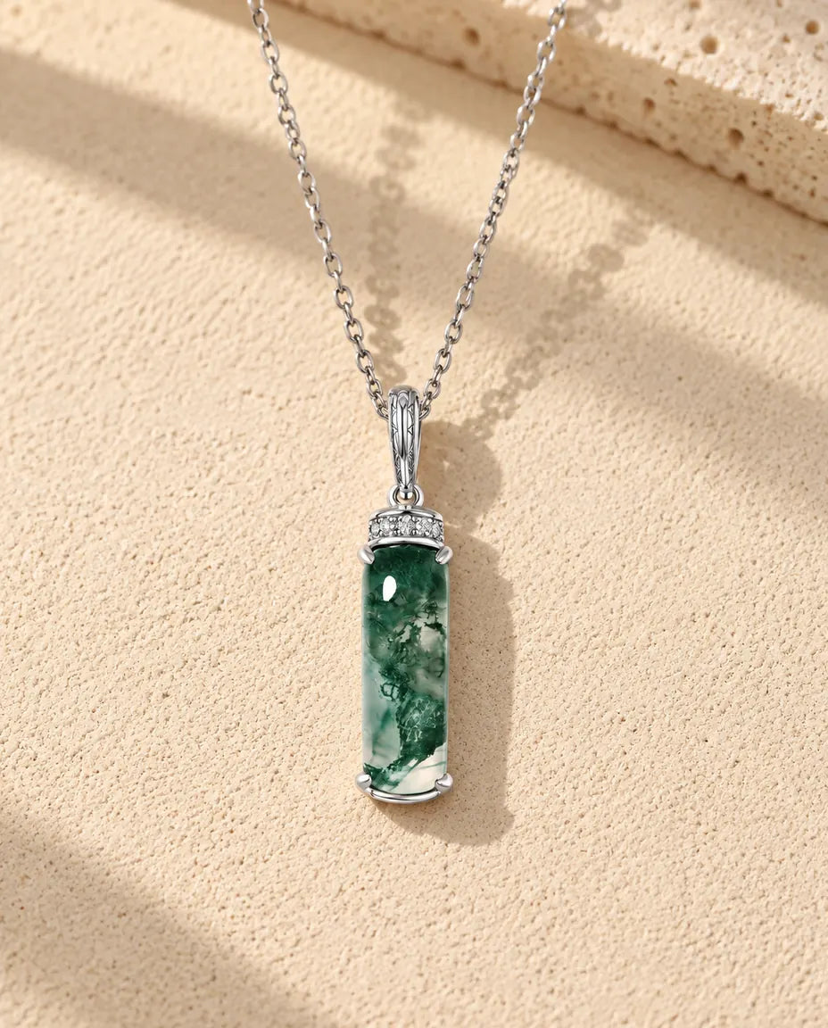 Moss Agate Bar Necklace in 925 Sterling Silver - lying on a cream textured surface beside a travertine block