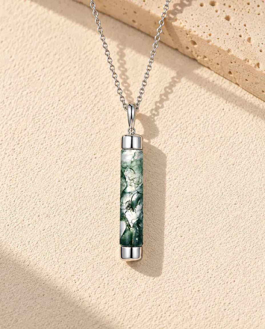 Moss Agate Bar Necklace in 925 Sterling Silver - lying on a cream textured surface beside a travertine block