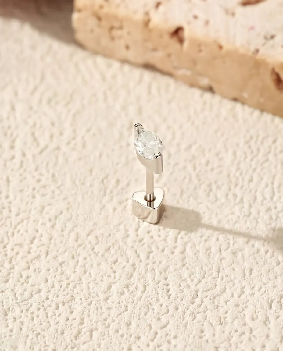 Marquise Moissanite Stud Earrings in 925 Sterling Silver - standing upright on its heart-shaped back on a cream textured surface