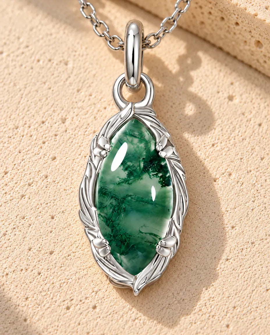Marquise Moss Agate Necklace in 925 Sterling Silver - lying on a cream textured surface beside a travertine block