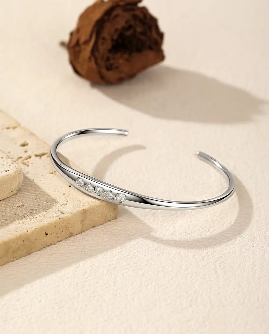 Moissanite Cuff Bracelet in 925 Sterling Silver - draped over a travertine slab