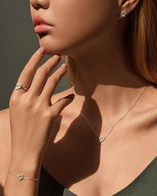 Model wearing the full moissanite heart set: necklace, bracelet, ring and stud earrings