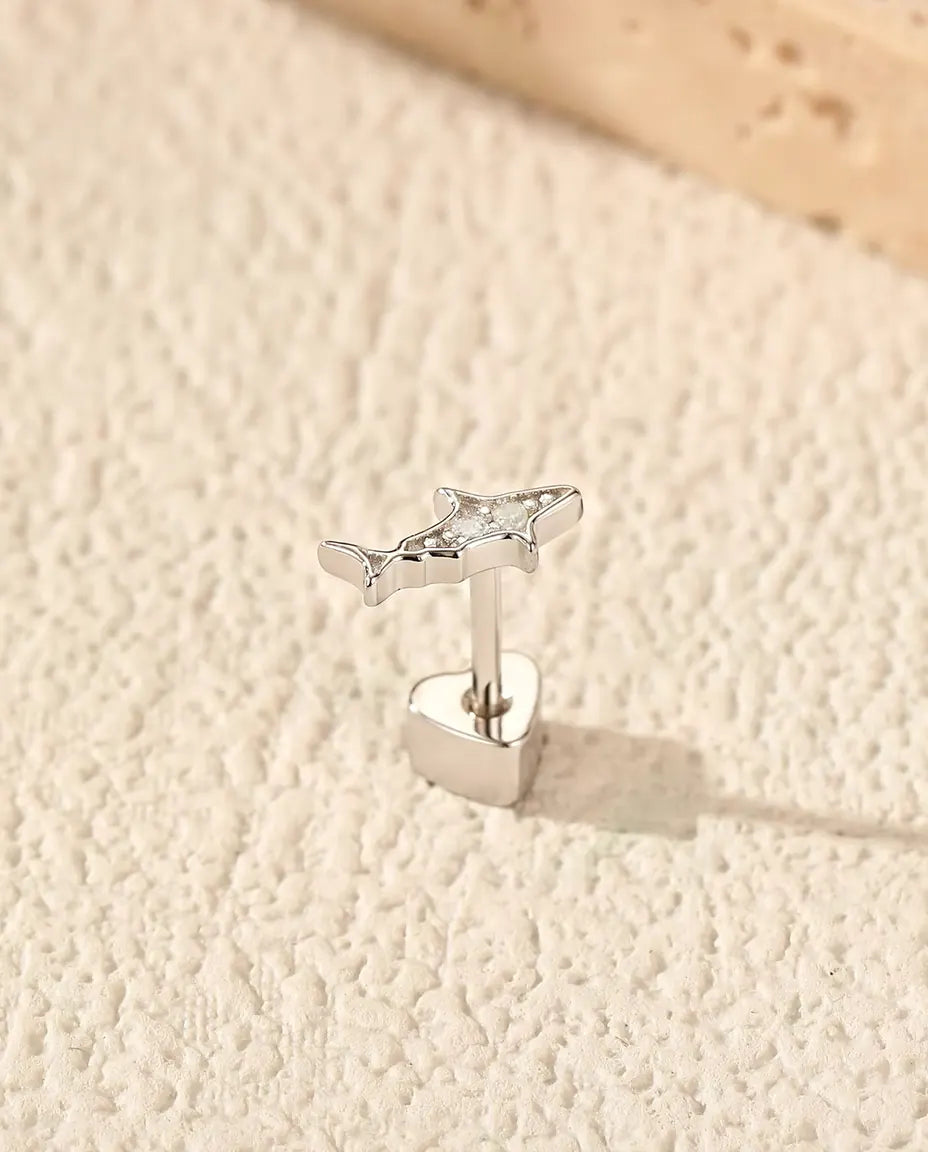 Shark Stud Earrings in 925 Sterling Silver with Moissanite - standing upright on its heart-shaped back on a cream textured surface