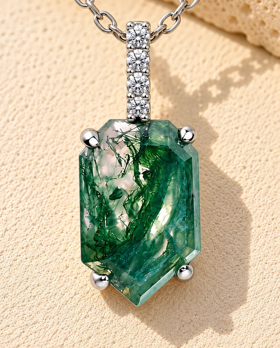 Moss Agate Shield Pendant Necklace in 925 Sterling Silver - lying on a cream textured surface beside a travertine block