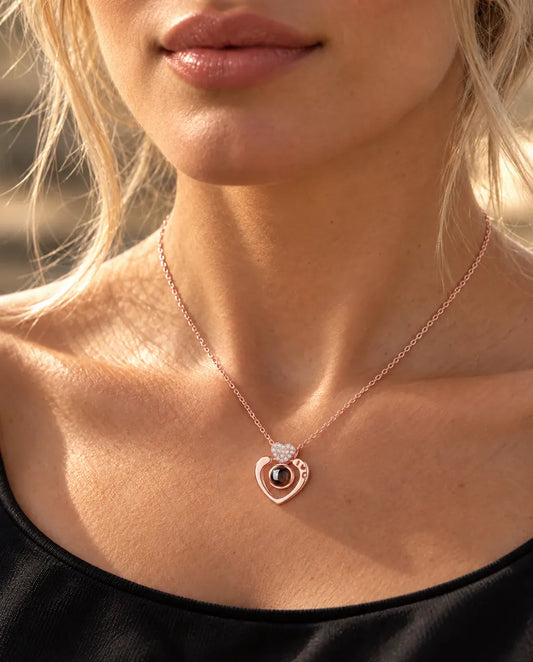 Woman in a black top wearing the rose gold tone open heart projection necklace