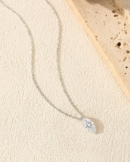 1 ct Marquise Moissanite Necklace in 925 Sterling Silver - laid in a soft curve on a cream textured surface