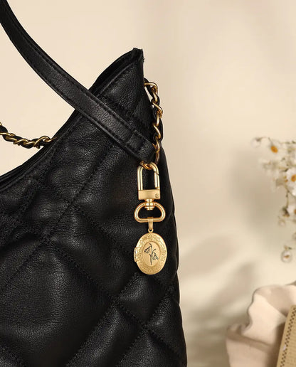 Gold locket keyring clipped to a black quilted handbag