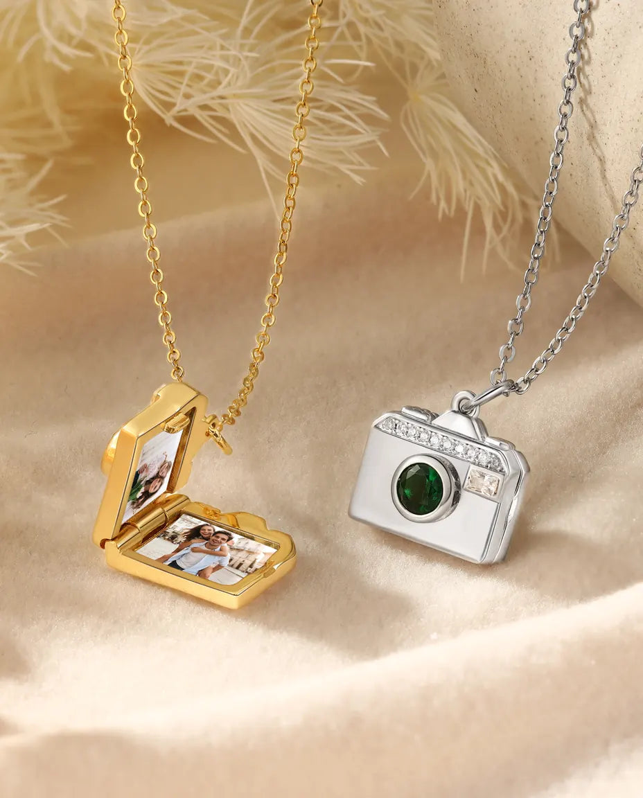 Camera locket open showing two photos inside, in gold and silver
