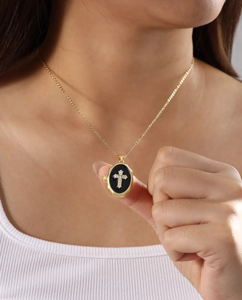 Woman wearing black enamel crystal cross locket necklace