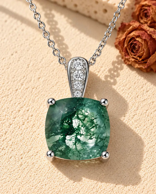 Cushion Moss Agate Pendant Necklace in 925 Sterling Silver - lying on a cream textured surface beside a travertine block