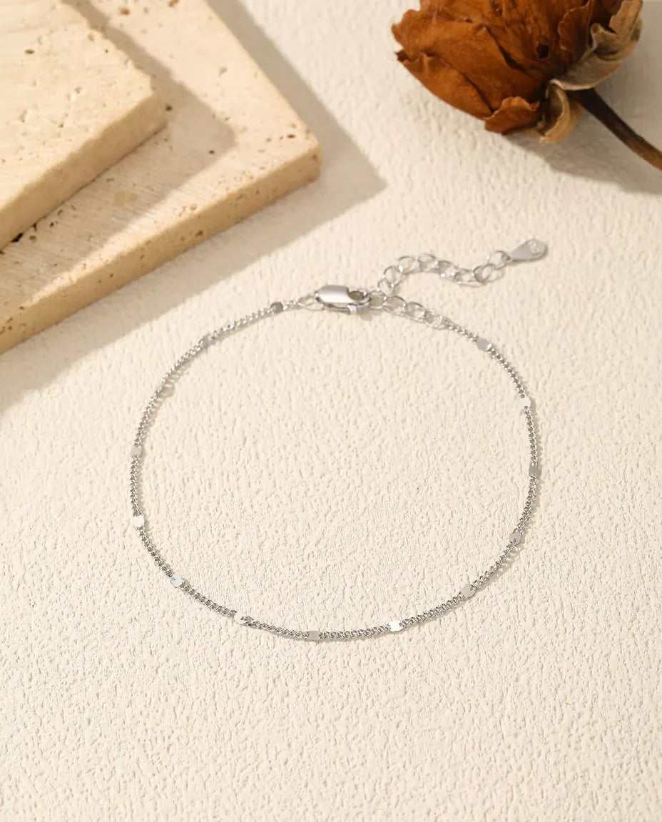 Sequin Chain Bracelet in 925 Sterling Silver - laid flat on a cream textured surface with the clasp and extender