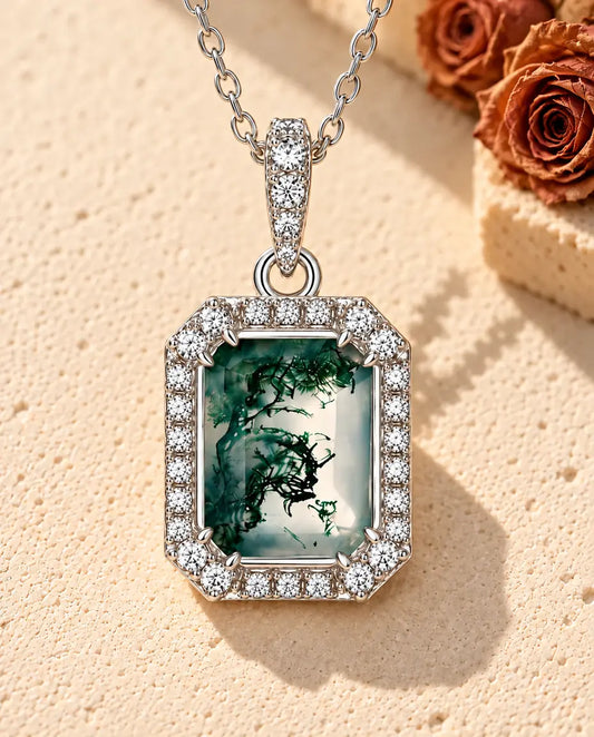 Emerald Cut Moss Agate Halo Necklace in 925 Sterling Silver - lying on a cream textured surface beside a travertine block
