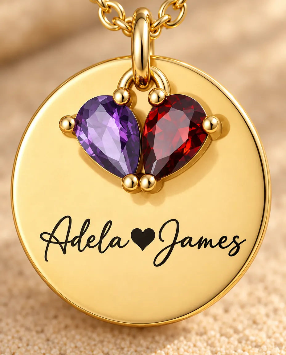 Macro detail of the two pear birthstones and the engraved script on the gold disc