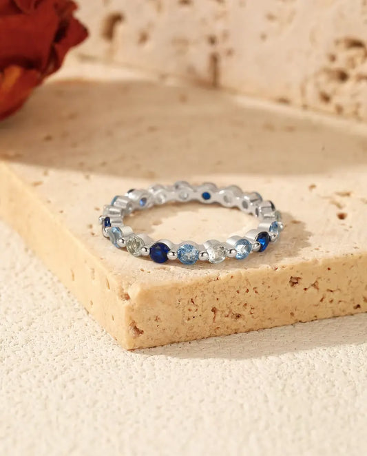 Blue Cubic Zirconia Eternity Ring in 925 Sterling Silver - lying on a travertine block