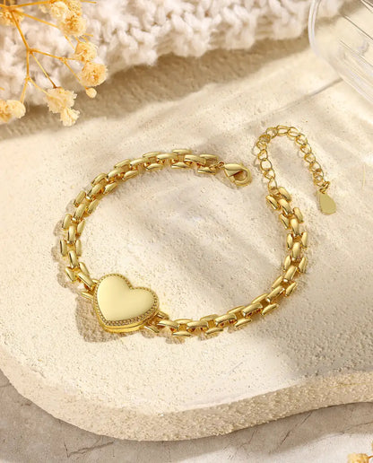 Gold heart locket bracelet closed on stone flatlay with dried flowers