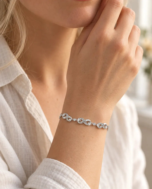Infinity name bracelet worn on the wrist, three charms engraved with names