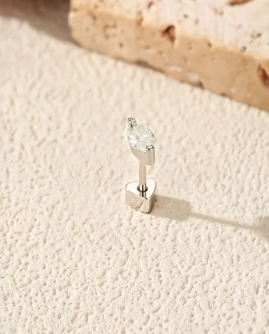 Marquise Moissanite Stud Earrings in 925 Sterling Silver - standing upright on its heart-shaped back on a cream textured surface