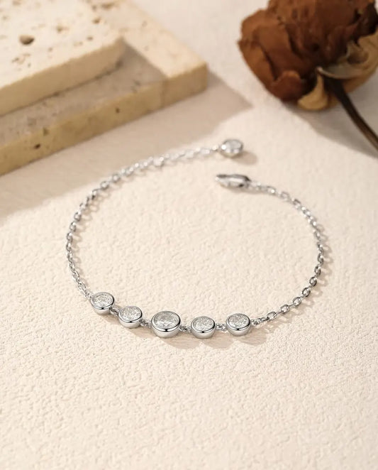 Moissanite Bezel Bracelet in 925 Sterling Silver - laid loosely on a cream surface with the clasp and extender