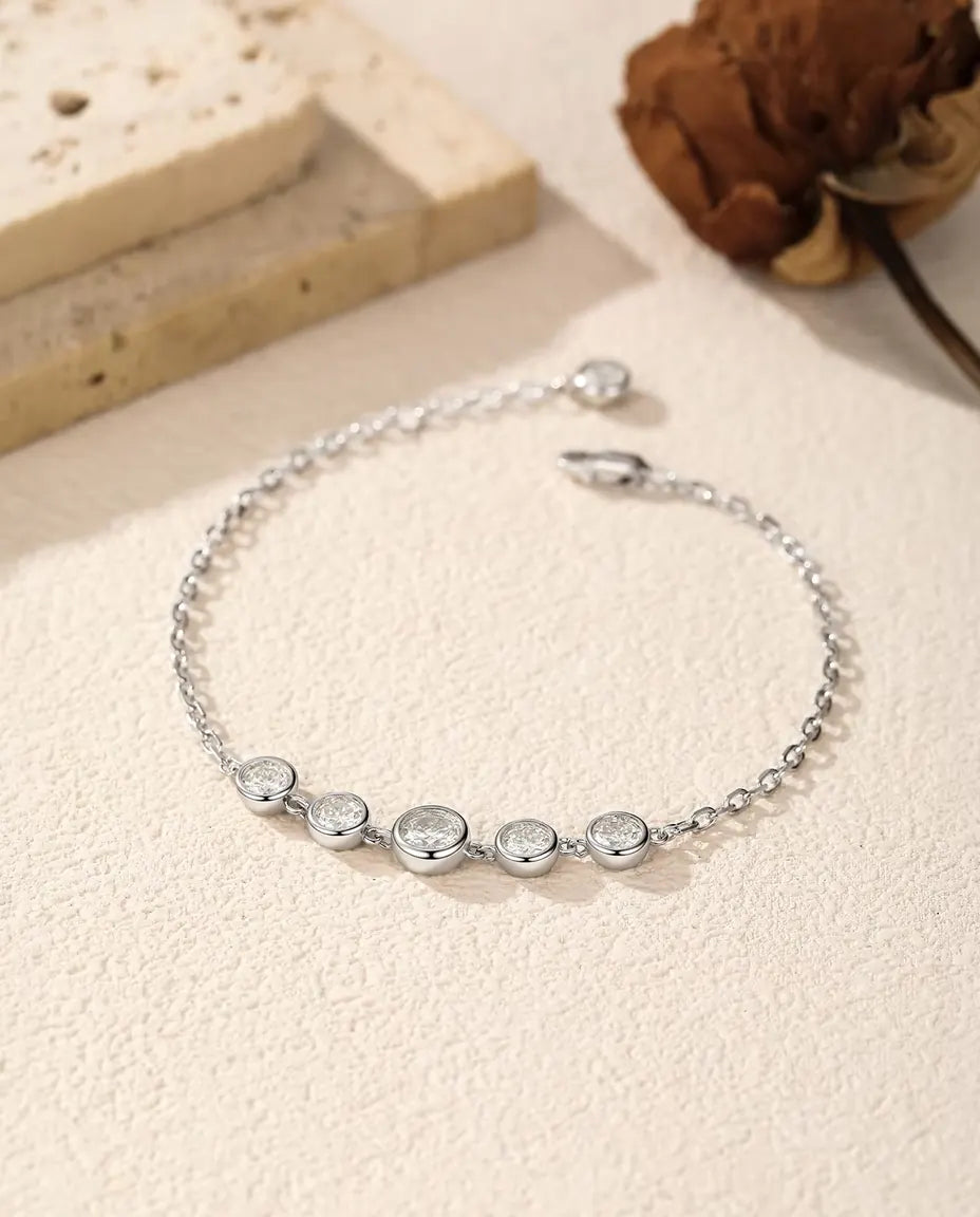 Moissanite Bezel Bracelet in 925 Sterling Silver - laid loosely on a cream surface with the clasp and extender