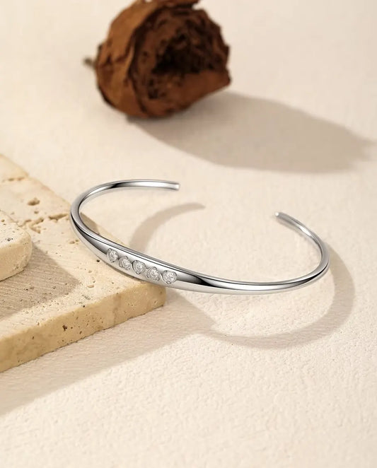 Moissanite Cuff Bracelet in 925 Sterling Silver - draped over a travertine slab