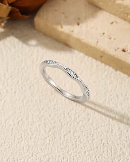 Moissanite Wave Ring in 925 Sterling Silver - standing upright on a cream textured surface