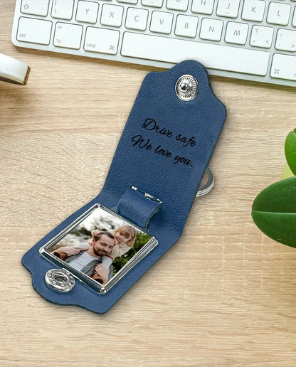 Blue faux leather monogram photo keyring on a desk with a plant