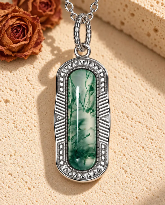 Moss Agate Bar Necklace in 925 Sterling Silver - lying on a cream textured surface beside a travertine block