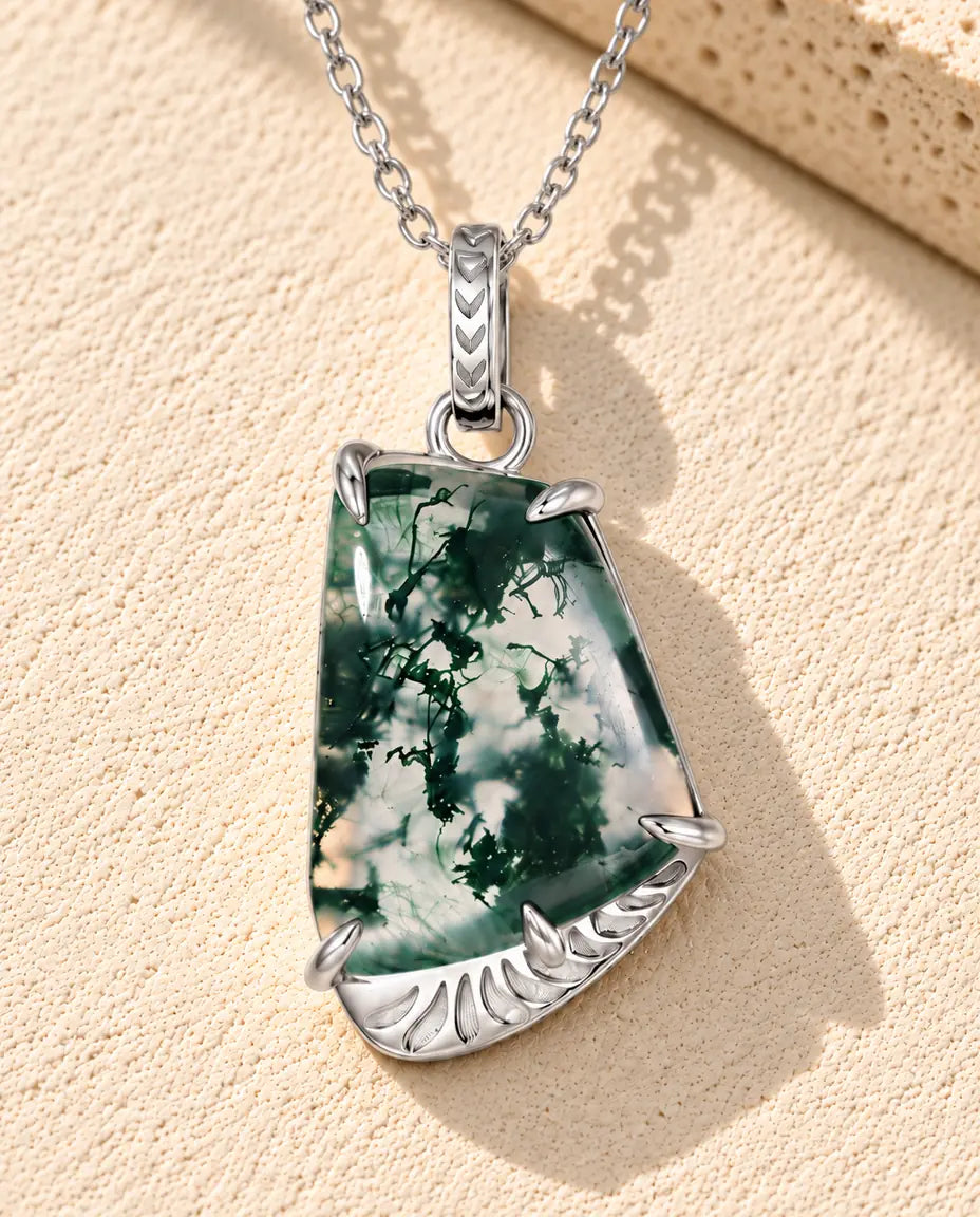 Moss Agate Slab Necklace in 925 Sterling Silver - lying on a cream textured surface beside a travertine block