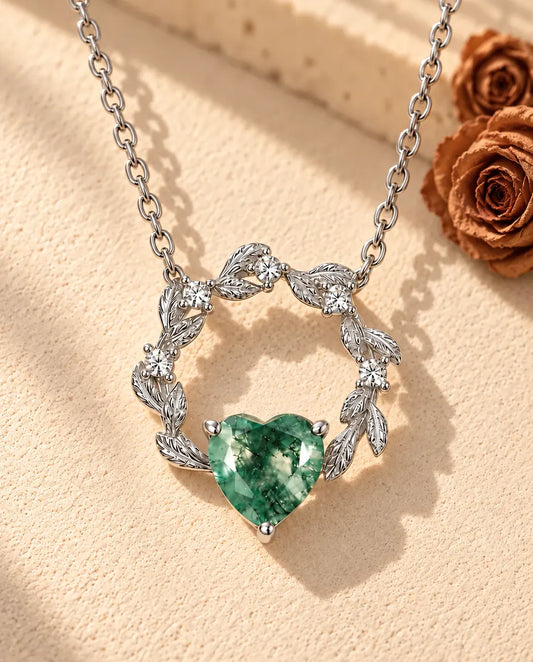 Moss Agate Heart Necklace in 925 Sterling Silver - lying on a cream textured surface beside a travertine block