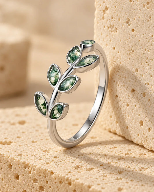 Olive Branch Moss Agate Ring - displayed on a travertine block