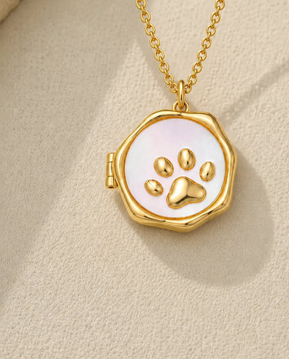 Gold paw print photo locket necklace with mother of pearl face on a cream stone