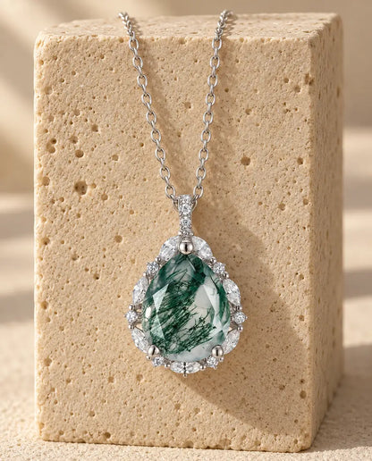 Moss Agate Pear Pendant - displayed on a travertine block
