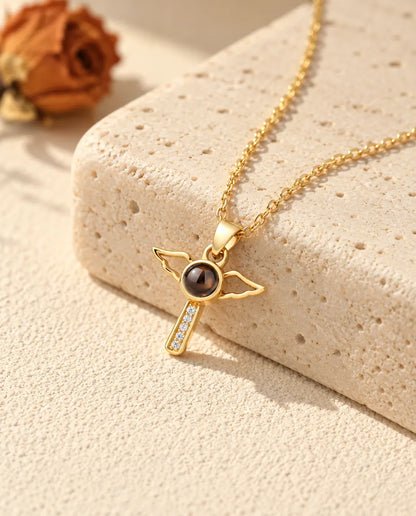 Personalised gold tone angel wings cross photo projection necklace on a travertine block