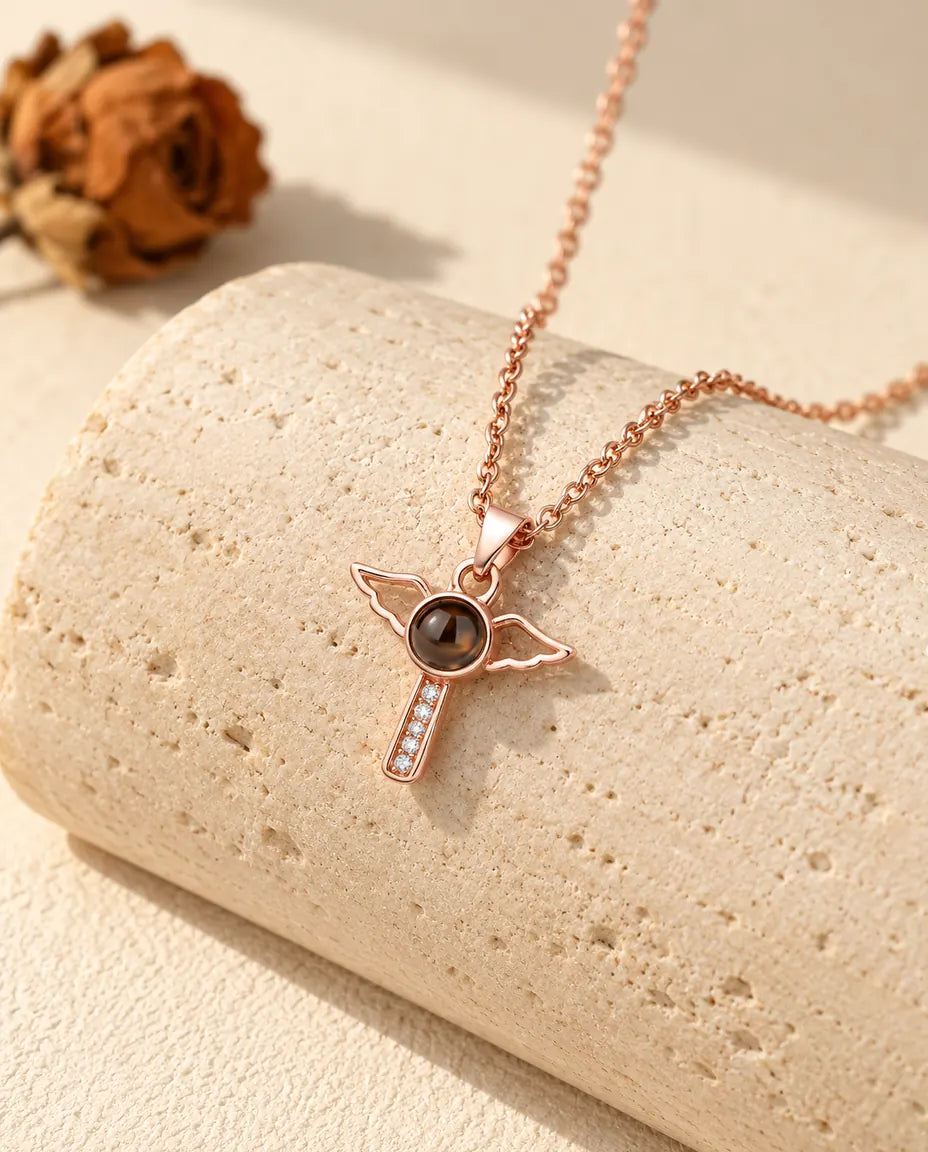 Rose gold tone angel wings cross projection necklace hanging over travertine