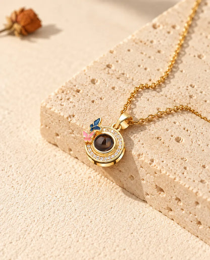 Gold tone butterfly circle projection necklace on a travertine block in warm sunlight