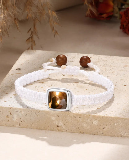 White braided bracelet with rounded square photo charm, flat lay