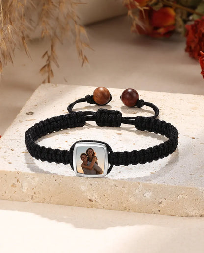 Black braided bracelet with rounded square photo charm, flat lay