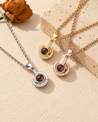 Silver tone, gold tone and rose gold tone crescent swirl pendants on travertine