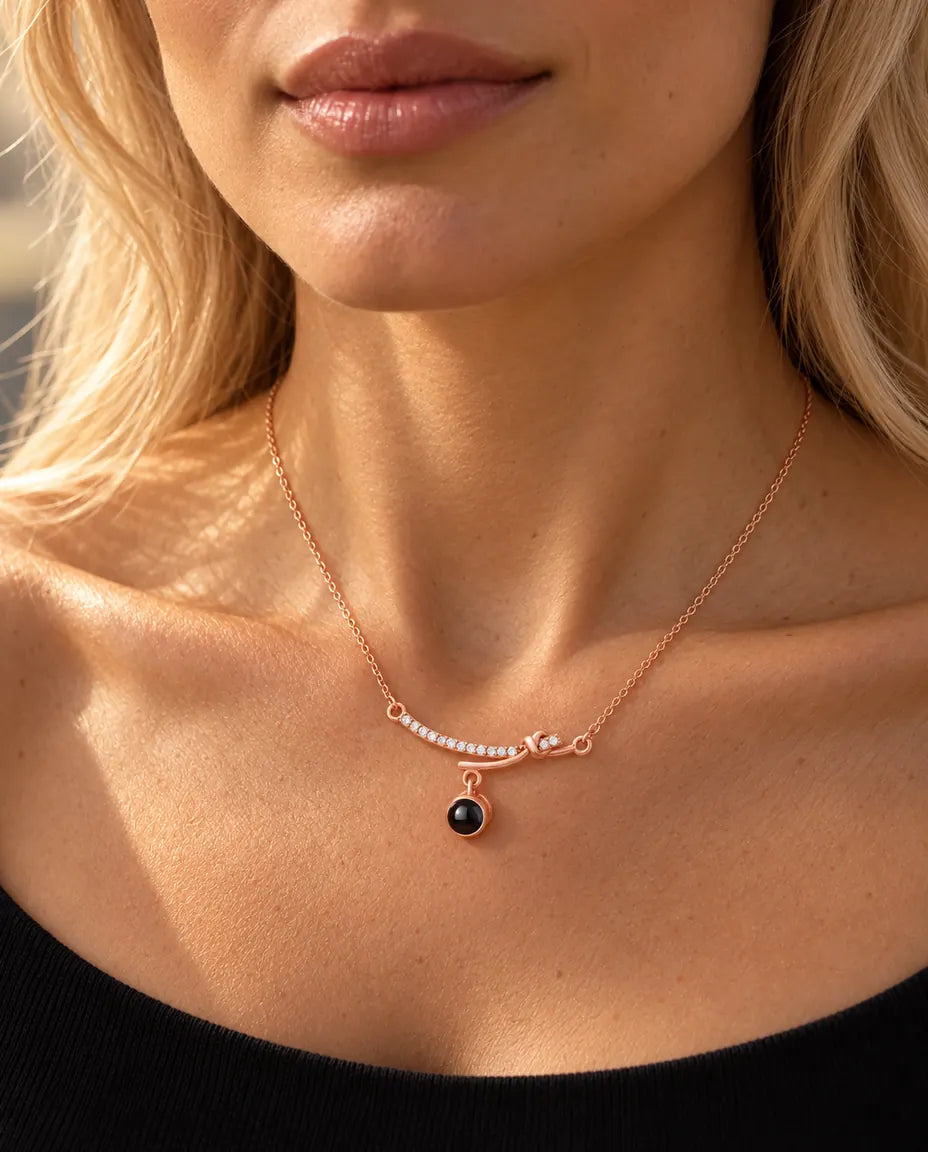 Woman in a black top wearing the rose gold tone curved bar projection necklace at her collarbone