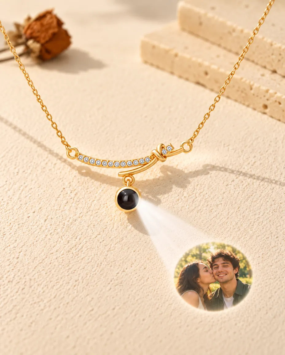 Gold tone curved bar necklace projecting a couple photo onto cream plaster