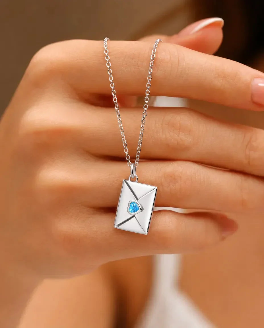 Silver envelope photo locket necklace with heart birthstone held in hand