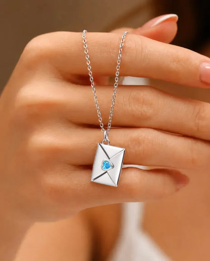 Silver envelope photo locket necklace with heart birthstone held in hand