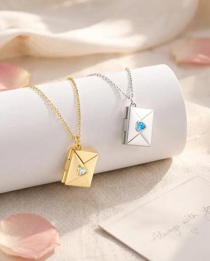 Envelope photo locket necklaces in gold and silver with heart birthstones, hanging side by side