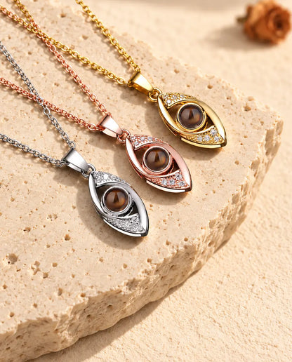Evil eye projection necklaces in silver tone, gold tone and rose gold tone fanned out on travertine