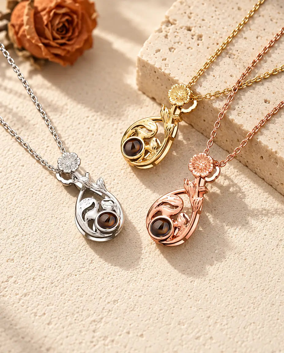 Silver tone, gold tone and rose gold tone daisy teardrop pendants on travertine